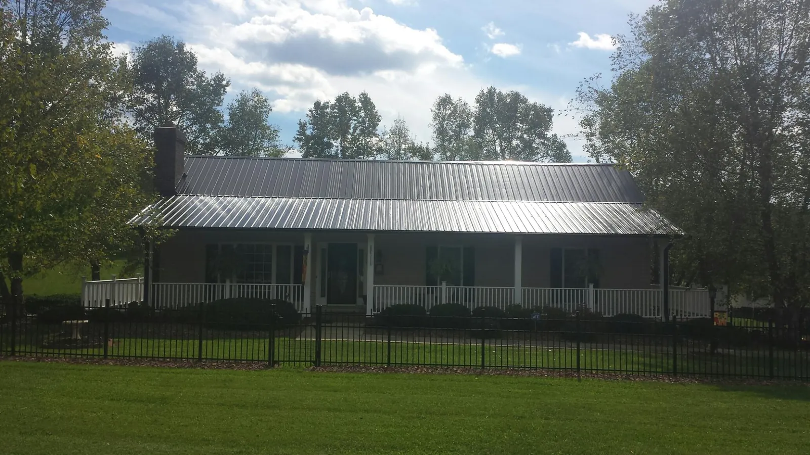 Gray metal roof on a brick ranch with a full width front porch — Gutter Guard Installation work by our crew in Collins